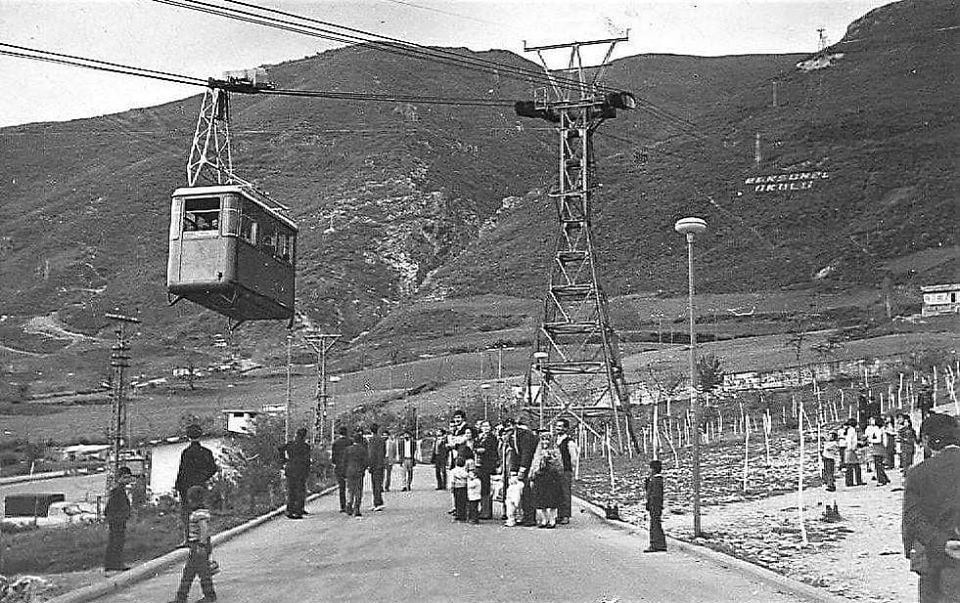 Türkiye'de erken dönem bir şehir teleferiği: kafes direk, tek kabin ve hattı izleyen kalabalık, siyah beyaz arşiv karesi