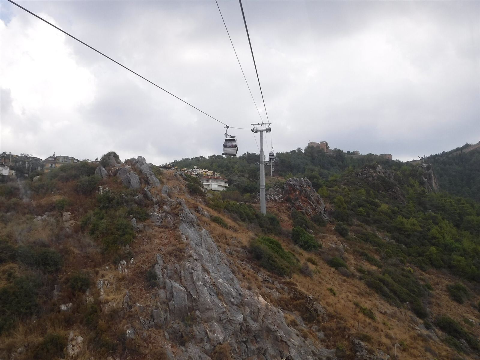 Alanya Teleferik hattı ve direkleri; arka planda sırta tırmanan kale surları