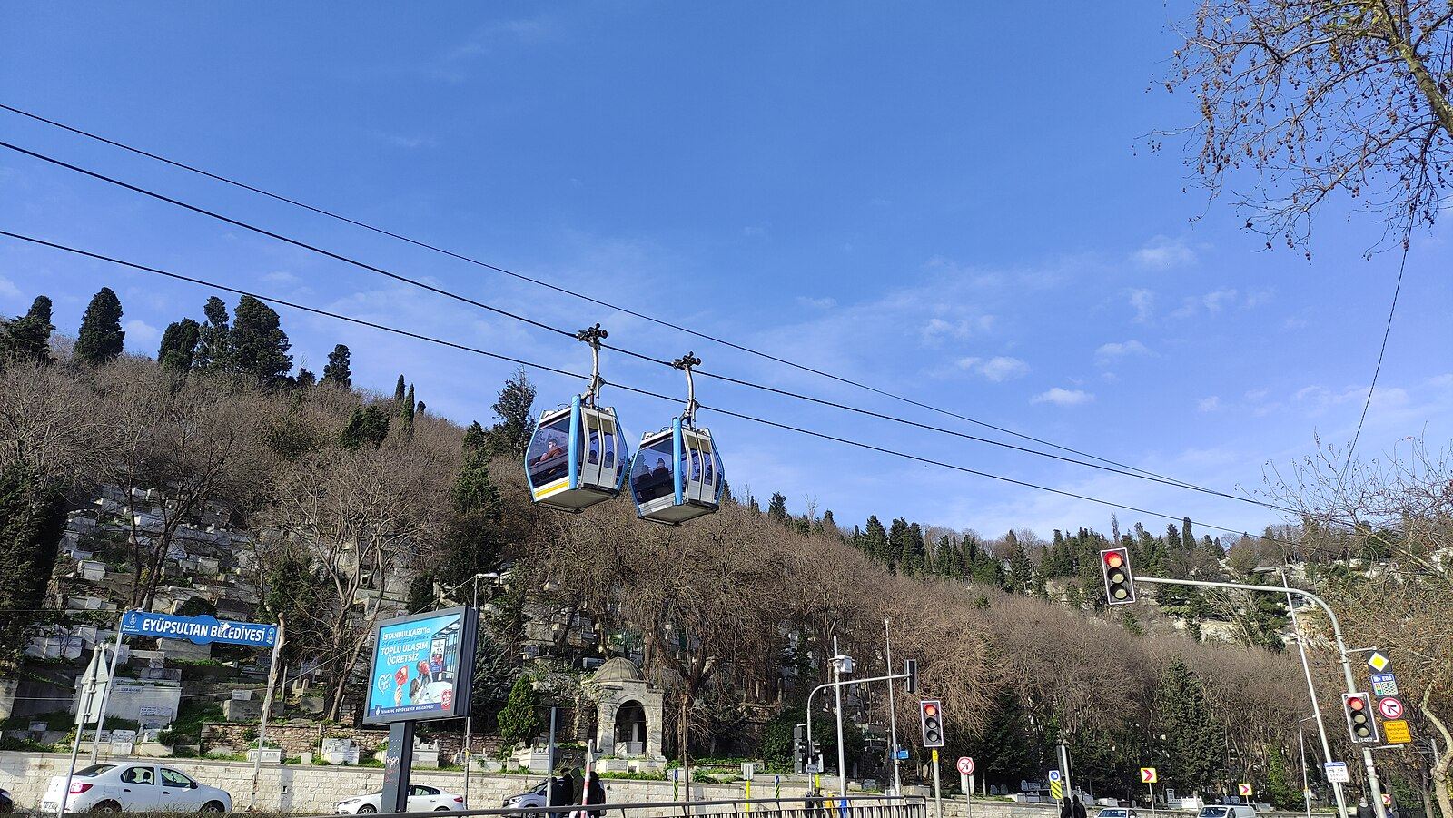 İki mavi teleferik kabini berrak gökyüzü altında Eyüp sırtlarındaki yamaç üzerinden geçiyor
